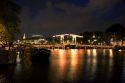 Skinny Magere drawbridge lit up at night on the Amstel River in Amsterdam, Netherlands.
