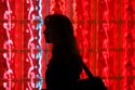 Woman walking past a glass block wall lit with red light at Washington Dulles International Airport, Washington D.C.