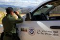 United States Border Patrol agent using binoculars to survey the new border fence that prevents illegal immagrant crossings at the U.S./Mexico border near San Diego, California